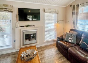 Un salon avec une cheminée, un canapé en cuir, une table basse et un téléviseur fixé au mur.