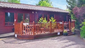 Puinen mökki, jossa on kuisti, sorapäällysteinen ajotie ja kyltti, jossa lukee ”Tay Lodge 1”.