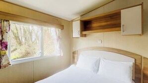 Una camera da letto con un letto, una finestra con tende, una testiera in legno e una mensola a muro.