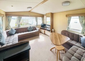 Ein gemütlicher Wohnbereich mit einer Couch, einem Fernseher, einem Kamin und einem Esstisch.