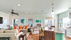 A spacious living area with a dining area, wooden flooring, and a ceiling fan. - Welcome to Sunset Dazed! See special rates & come enjoy the beach! (Galveston)