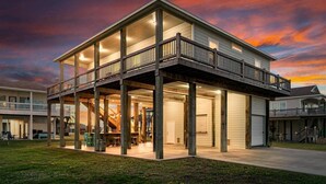 A two-story house with a balcony, a covered patio, and a garage. - Welcome to Sunset Dazed! See special rates & come enjoy the beach! (Galveston)