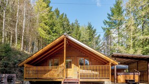 Una baita di legno con un balcone, un piccolo portico e una zona esterna coperta.