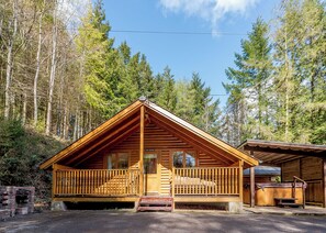 A wooden cabin with a balcony, a small porch, and a covered outdoor area. - Timber lodge set in an elevated position with views of the lake. (Webbery, Bideford)