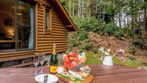 Un tavolo di legno apparecchiato con una bottiglia di champagne, frutti di mare e fiori, con una cabina sullo sfondo.
