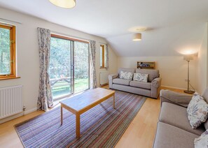Un salon avec un canapé, une table, un lampadaire et une vue dégagée sur l’extérieur grâce à une grande fenêtre.