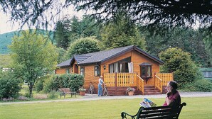 A wooden cabin with a porch, a bench, and a bicycle. - Log cabin with one double with en suite shower and two twin. (Ettrick Valley, Nr Hawick)