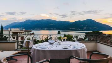 A round table set for dining with a view of mountains and a lake.