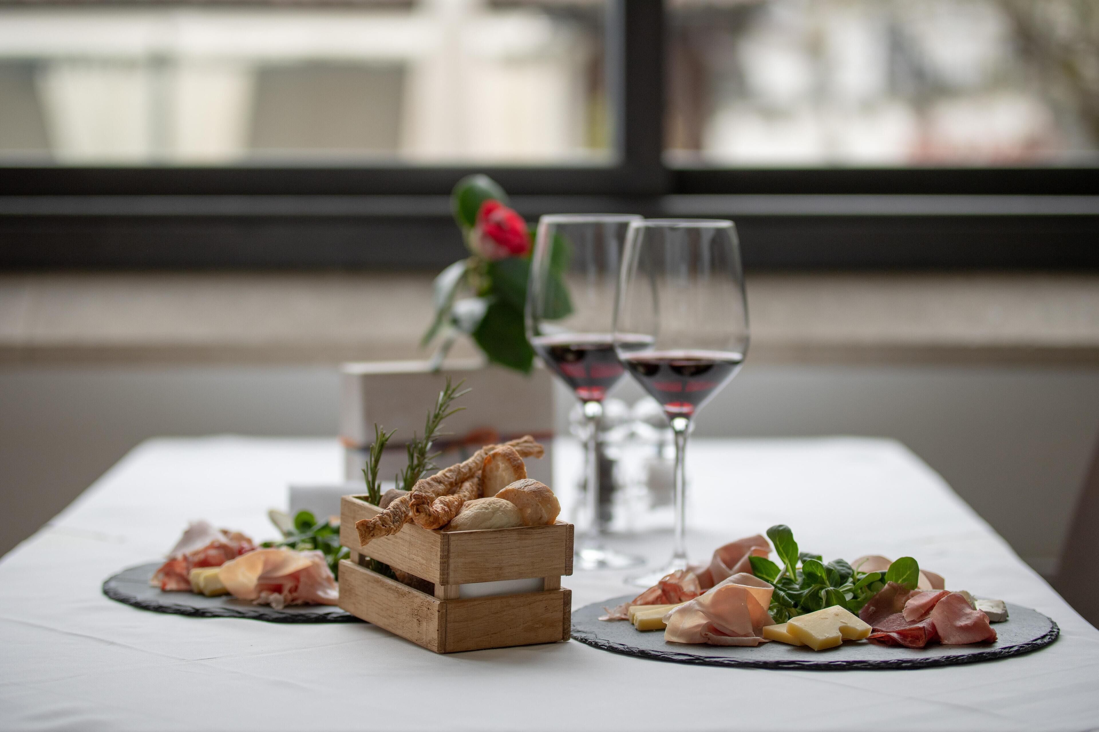 Taula amb diversos plats i dues copes de vi vermell.