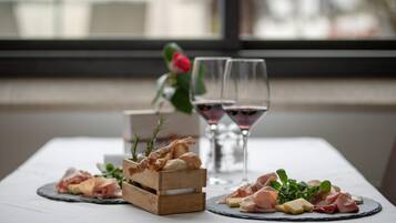 Una mesa con varios alimentos y dos copas de vino tinto.
