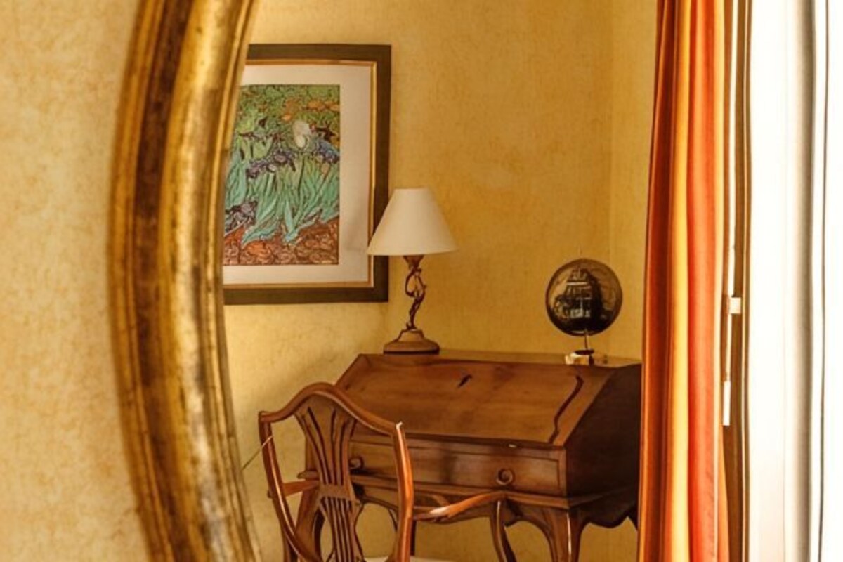 Une pièce comprenant un bureau en bois, une chaise, une lampe, un globe terrestre et un tableau encadré accroché au mur.