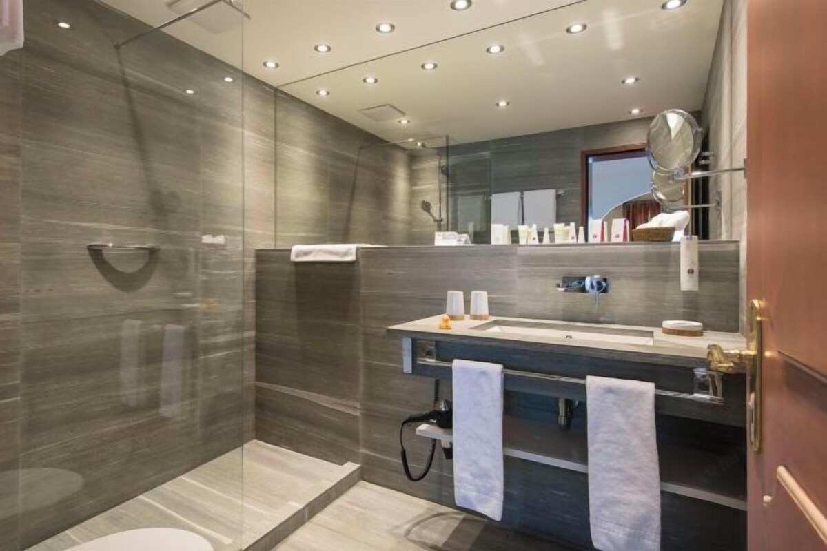 Un baño moderno con cabina de ducha de vidrio, tocador con espejo y perchero.