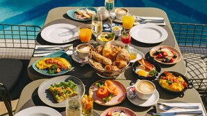 Una mesa de comedor dispuesta con alimentos para el desayuno y una piscina al fondo.