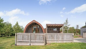 A wooden cabin with a curved roof, a fenced yard, and a gravel path leading to the entrance. - 0 bedroom accommodation in Great Busby (Great Busby)