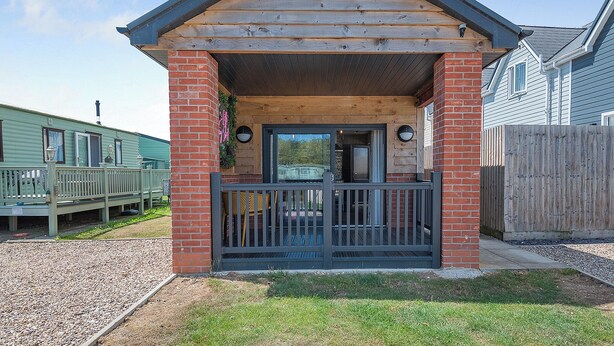 Een houten gebouw met een veranda, bakstenen muren en een metalen poort.