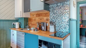 Een keuken met houten kastjes, een betegelde spatwand en een inbouwoven.