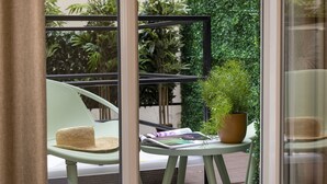 A green chair with a woven basket, a small round table with a potted plant, and a magazine. - 1 bedroom apartment with private terrace - 44m2 (Paris)