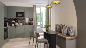 A modern kitchen with a built-in microwave, a dining area with a bench, and a large window providing a view of greenery outside. - 1 bedroom apartment with private terrace - 44m2 (Paris)