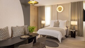 A hotel room with a bed, bedside tables, a desk with a chair, a potted plant, and a TV. - 1 bedroom apartment with private terrace - 44m2 (Paris)