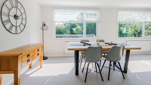 Una habitación moderna con un escritorio de madera, dos sillas, un reloj de pared grande y una ventana con persianas.