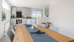 Cocina moderna con armarios blancos, una mesa de madera y un tapete azul.