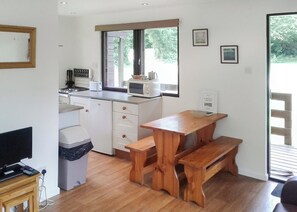 A compact kitchen with a microwave, toaster, and sink. There is a wooden bench and a small table.