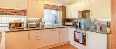 A modern kitchen with white cabinets, a microwave, toaster, kettle, and a refrigerator.