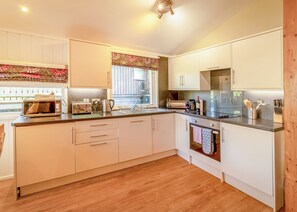 A modern kitchen with white cabinets, a microwave, toaster, kettle, and a refrigerator.