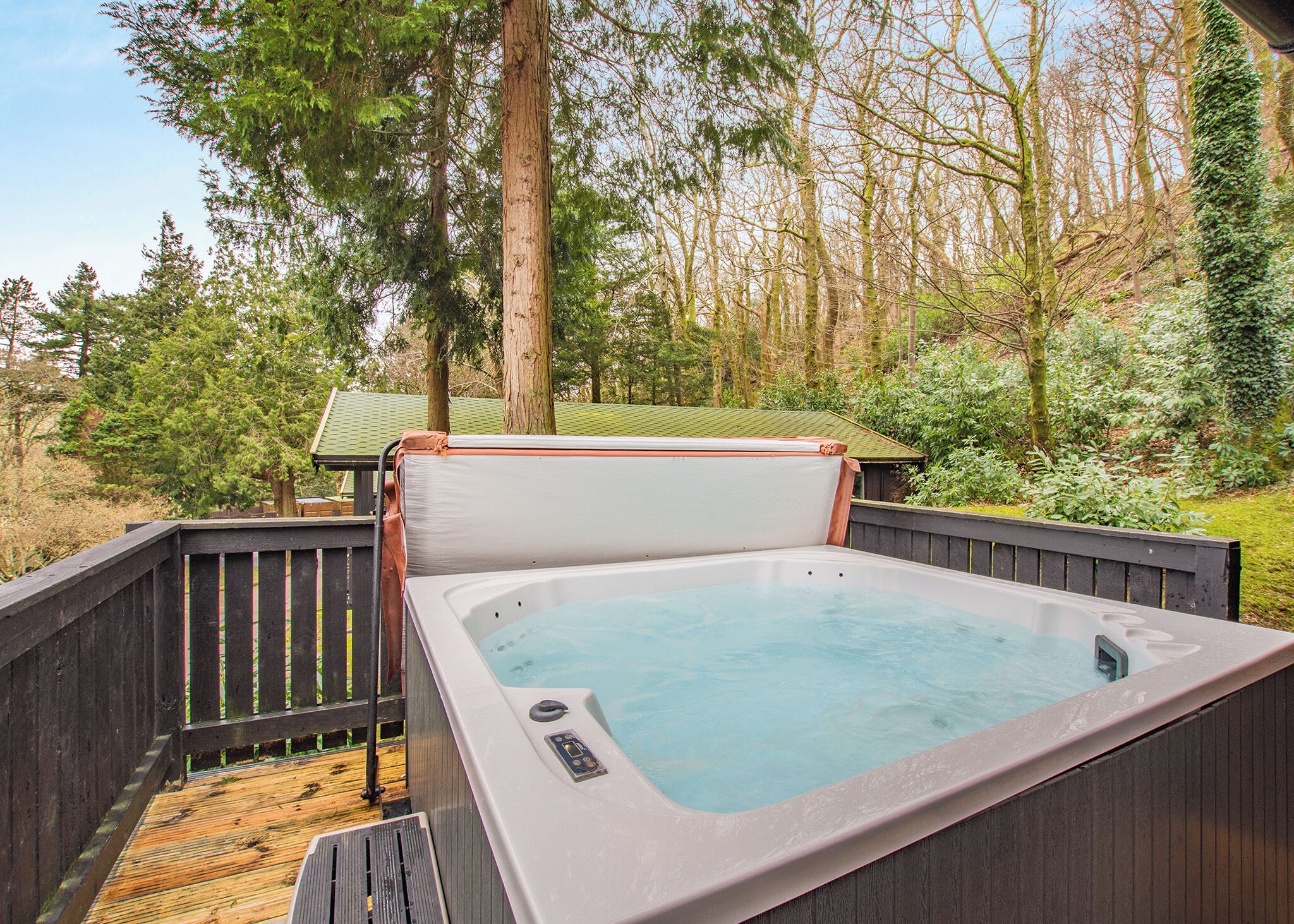 A hot tub on a wooden deck with a view of a forest.