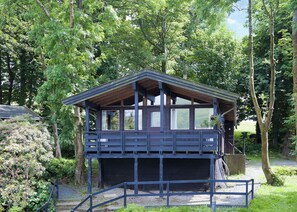 A wooden cabin with a balcony, surrounded by trees.