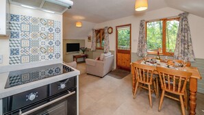 Een keuken met een fornuis, oven en een eethoek met een tafel en stoelen.