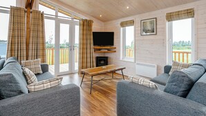 A cozy cabin interior with a TV, sofa, and fireplace. - Field View Lodge (Pet) (Bretby, Derbyshire)