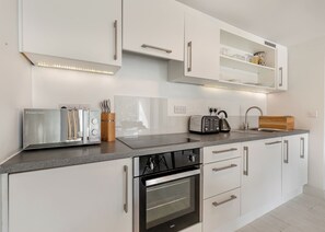 Une cuisine moderne dotée d’appareils électroménagers intégrés, d’un plan de travail et de meubles de rangement blancs.