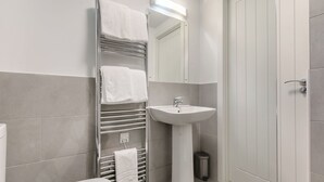 Un baño con inodoro, lavamanos, toallero y espejo.