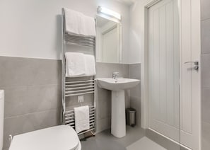 Ein Badezimmer mit Toilette, Waschbecken, Handtuchhalter und Spiegel.