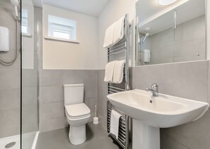 A modern bathroom with a toilet, shower, and sink.