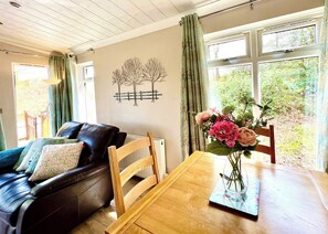 Een woonkamer met een houten eettafel, een leren bank en een bloemenvaas.