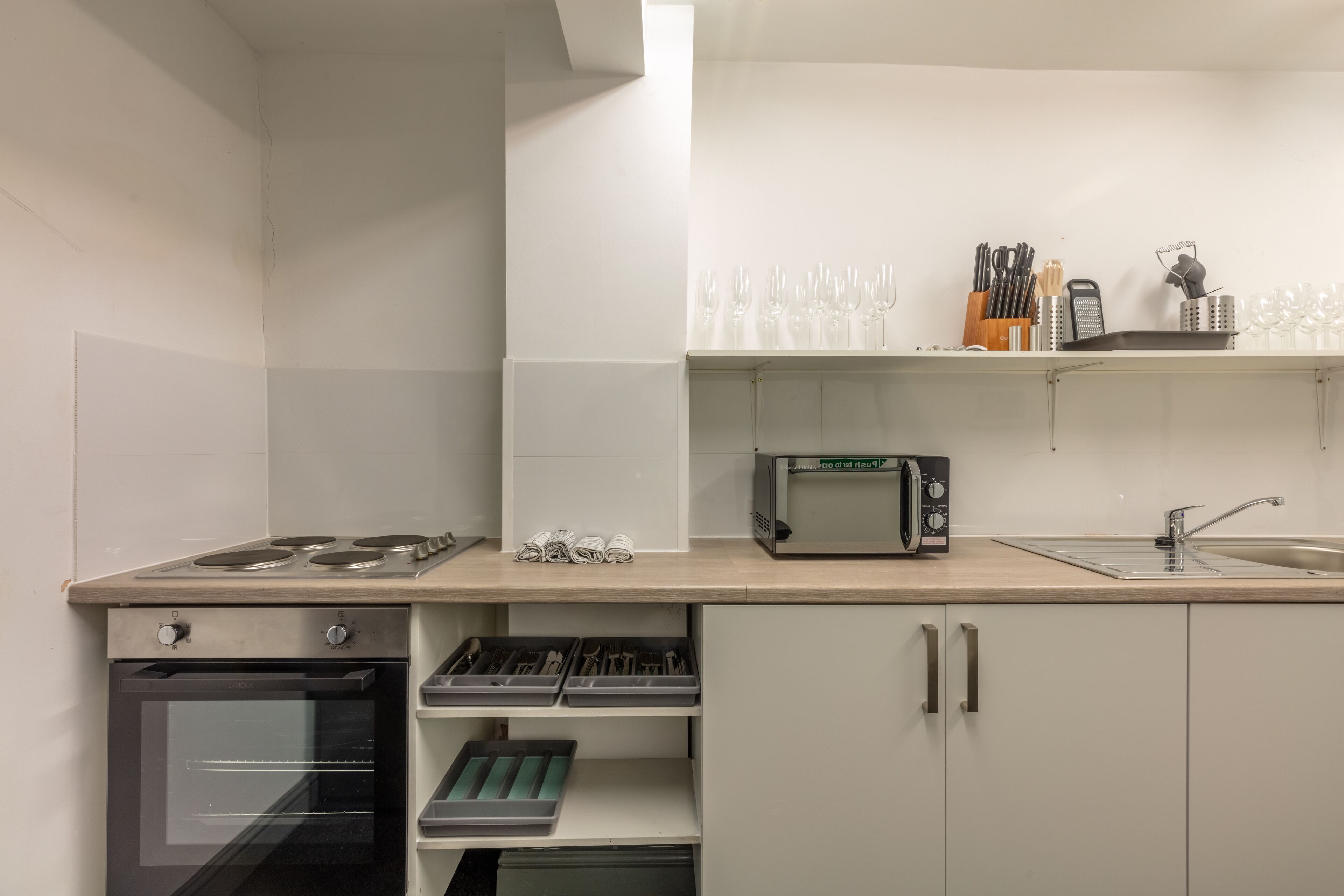A modern kitchen with a built-in oven, microwave, and stainless steel sink.
