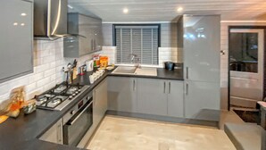 Una cocina moderna con armarios grises, una estufa de acero inoxidable y una ventana con persianas.