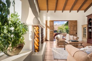 Relax in a spacious room with a seating area, wooden cabinet, and potted plant, offering a doorway to an outdoor space with a view.