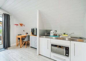 Una cocina moderna con comedor, hervidor, cafetera y horno empotrado.