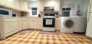 A kitchen with white cabinets, a microwave, stove, and a washing machine.