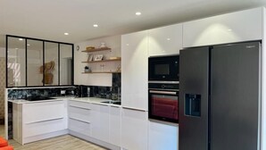 A modern kitchen with white cabinets, a black refrigerator, and built-in appliances.