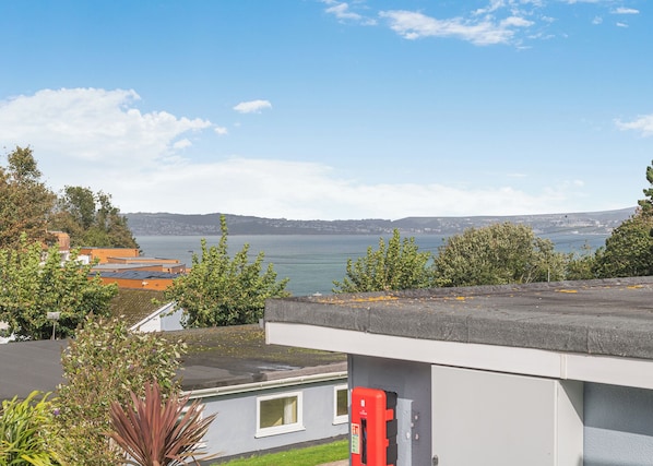 A residential area with a view of a body of water, a red fire hydrant, and a building with a grey roof. - Silver 1 Bedroom Chalet (Brixham, Torbay)