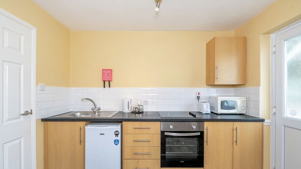 A compact kitchen with a refrigerator, oven, microwave, and sink.