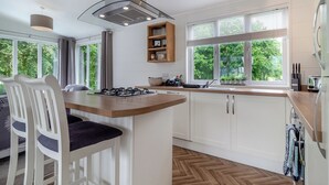 Una cocina moderna con una isla central, armarios blancos, una estufa a gas y una ventana con vista a zonas verdes.