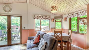 A cozy room with a sofa, dining table, chairs, and a ceiling fan.