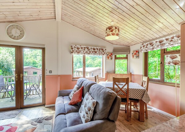 A cozy room with a sofa, dining table, chairs, and a ceiling fan.