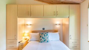 A bedroom with a bed, bedside lamps, a headboard, and wooden cabinets.