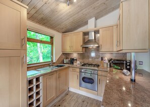 A modern kitchen with wooden cabinets, a stainless steel range, and a built-in oven.